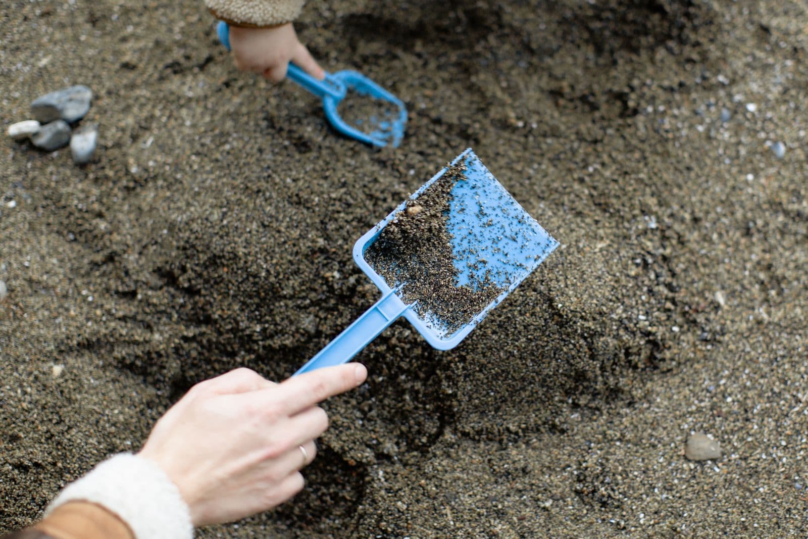 Kinderhände graben mit Schaufeln im Sand